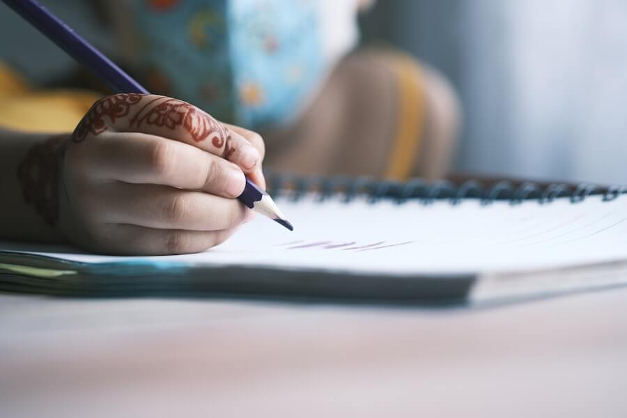 A child concentrating while writing in a notebook.